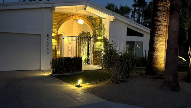 Una casa moderna con garaje, entrada arqueada y camino de acceso bien iluminado.