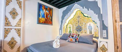 A bedroom with a bed, a painting, and a decorative wall.