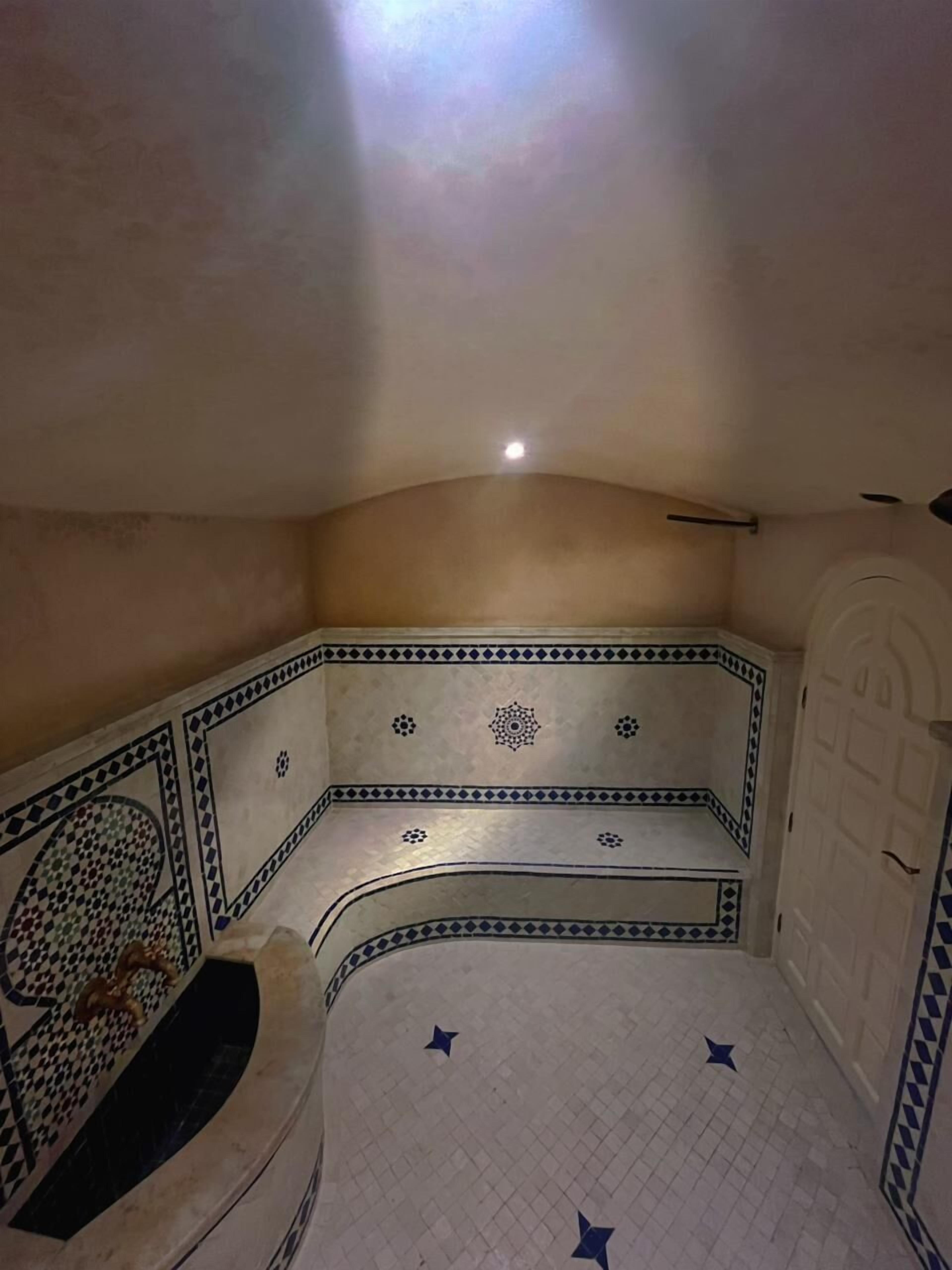 Una habitación con un banco curvo, paredes decoradas y suelo de baldosas.
