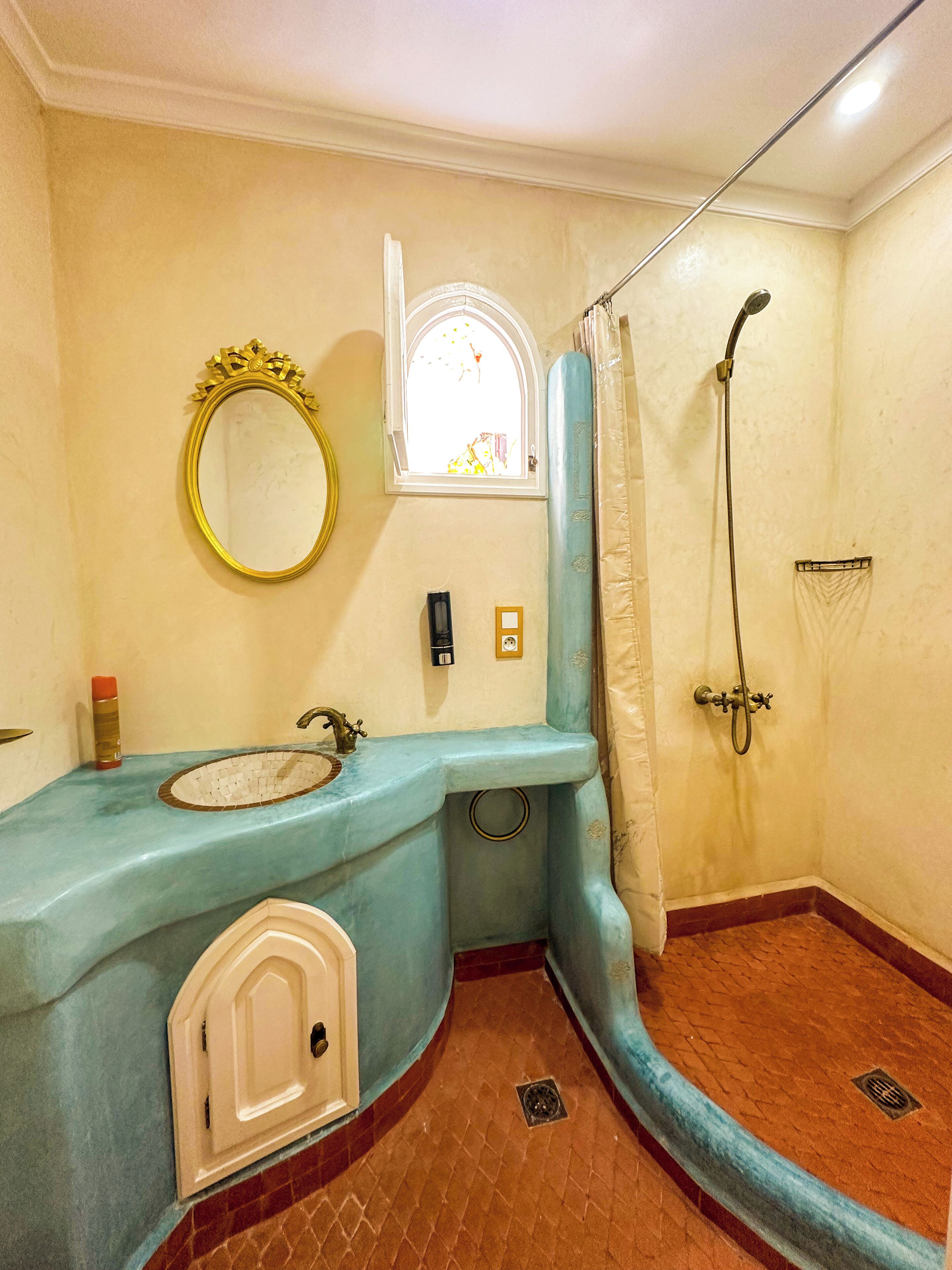 Un baño con lavamanos, espejo, ventana, ducha y puerta.