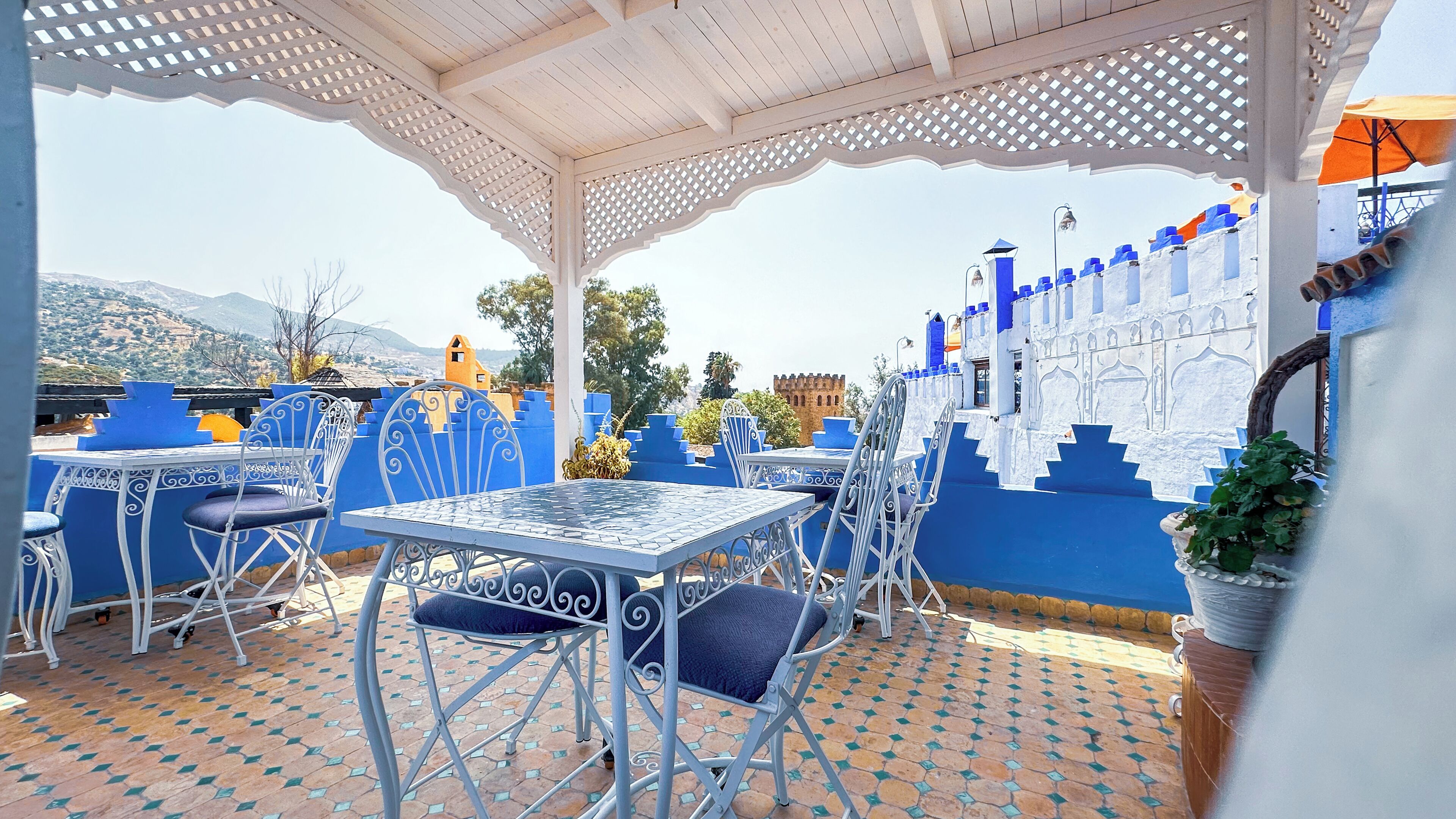 An outdoor patio with a white pergola, blue and white decor, and a tiled floor.