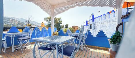 An outdoor patio with a white pergola, blue and white decor, and a tiled floor.