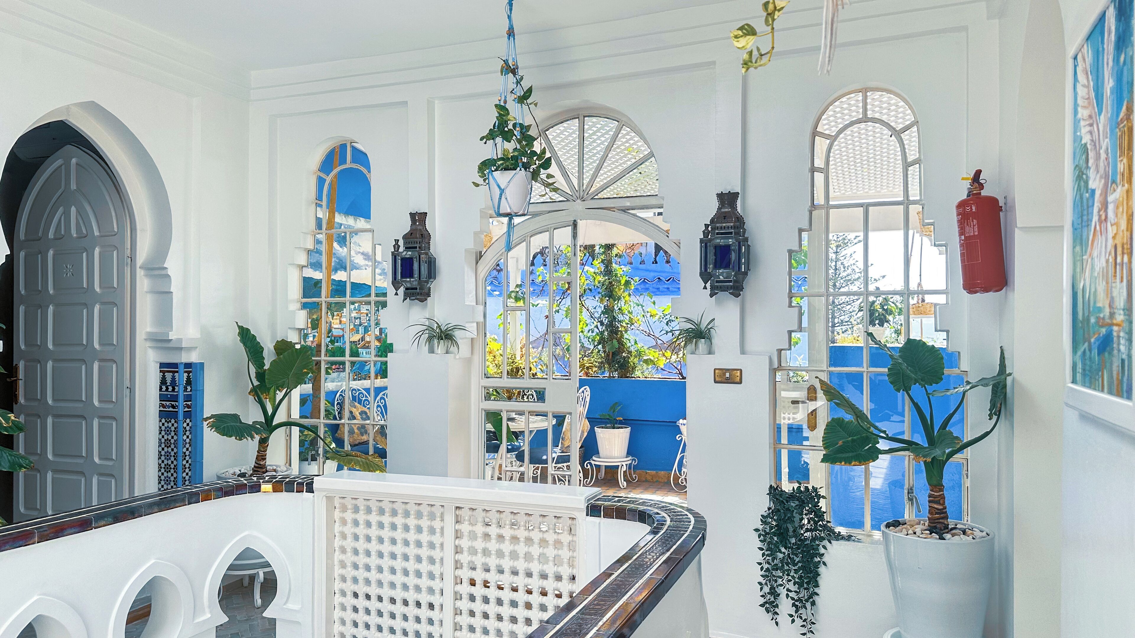 A spacious interior with high ceilings, large windows, and a variety of potted plants.