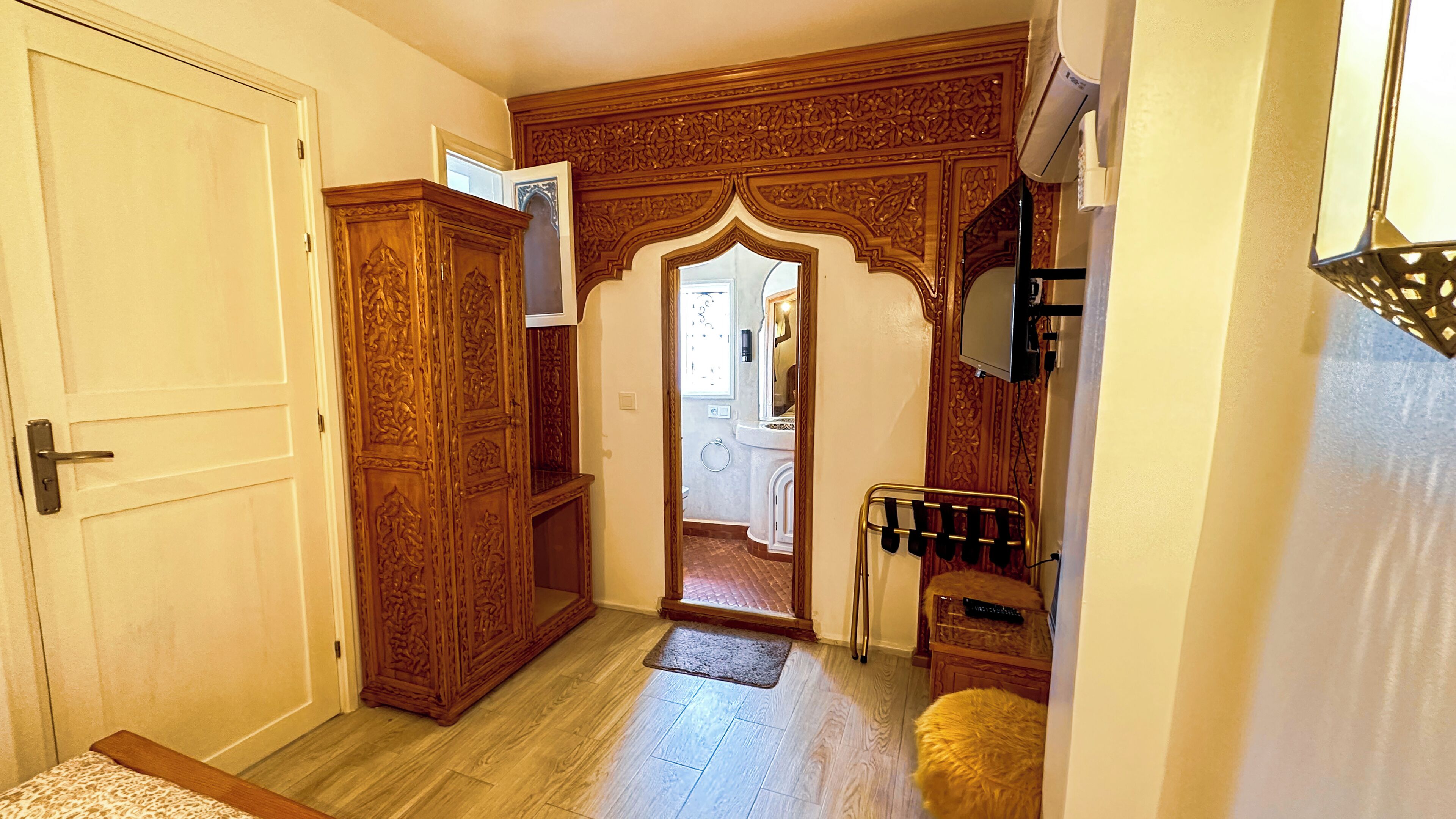 A hallway with a wooden door, a mirror, and a small rug.