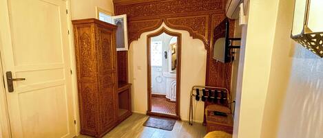 A hallway with a wooden door, a mirror, and a small rug.