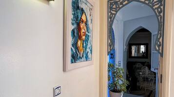 A hallway with a framed painting, a decorative mirror, and a potted plant.