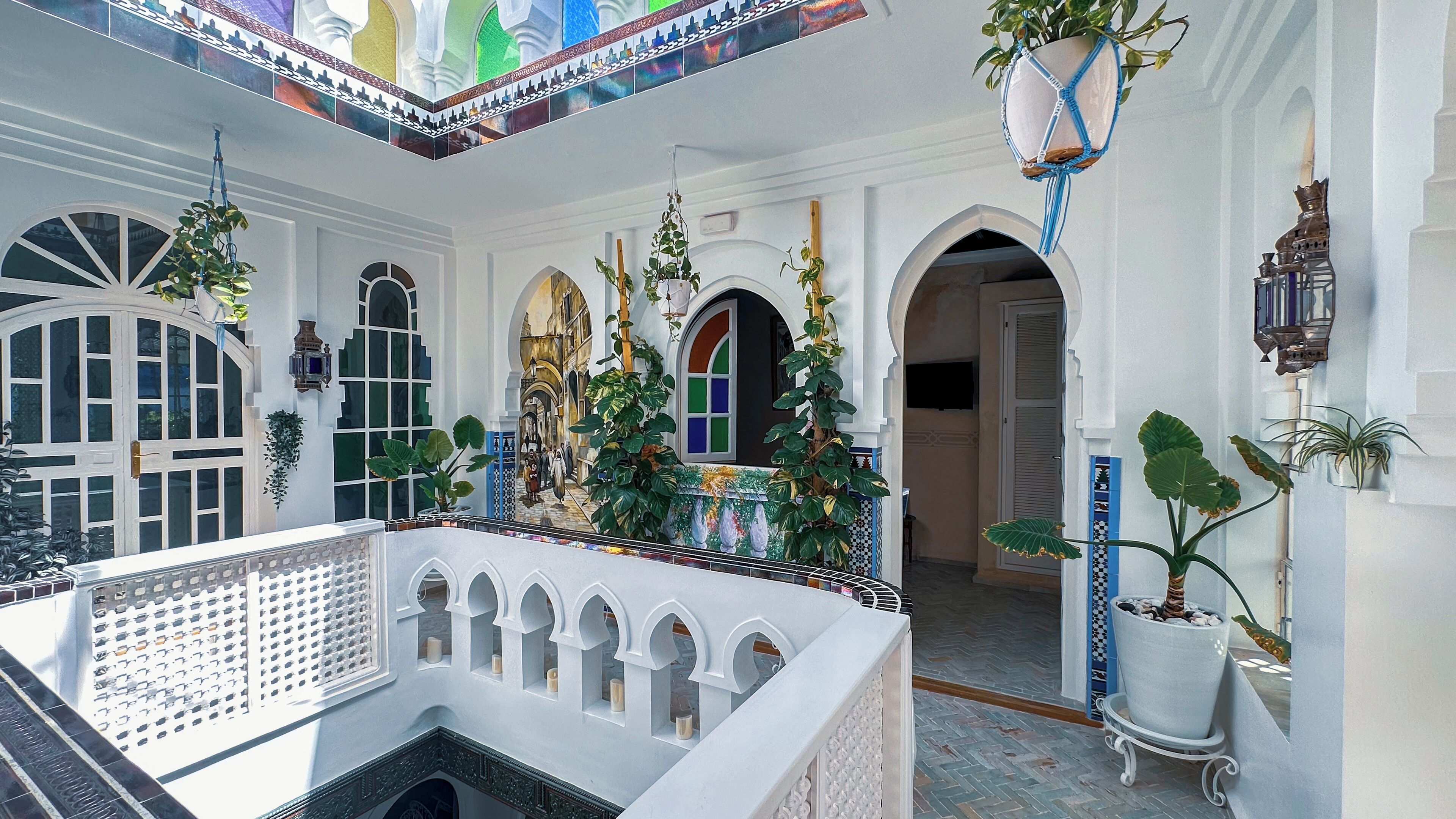 A traditional courtyard with arches, potted plants, and a tiled floor.