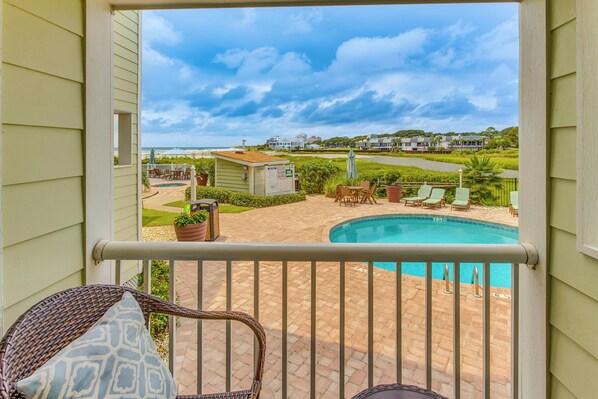 A balcony with a view of a swimming pool, outdoor furniture, and a small shed. - On-Site Ocean Access: Condo in Myrtle Beach (Myrtle Beach)