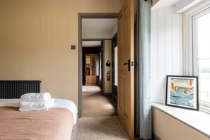 Hotellihuone, jossa on sänky, seinällä taulu ja näkymä käytävään.