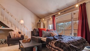 Ett mysigt sovrum med en säng, en soffa, ett skrivbord och ett fönster med gardiner.