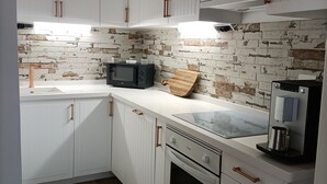 A kitchen with white cabinets, a brick backsplash, a microwave, a coffee maker, and a toaster. - Beautiful apartment with garden and jacuzzi in Puerto de la Cruz (Puerto de la Cruz)