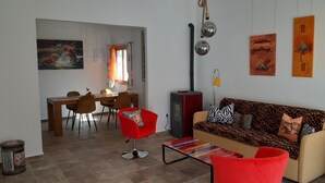 A living room with a sofa, red chairs, a dining table, and a fireplace. - Beautiful apartment with garden and jacuzzi in Puerto de la Cruz (Puerto de la Cruz)