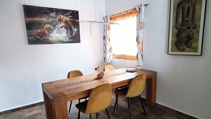 A dining area with a wooden table, four chairs, a window with curtains, and two framed artworks on the walls. - Beautiful apartment with garden and jacuzzi in Puerto de la Cruz (Puerto de la Cruz)