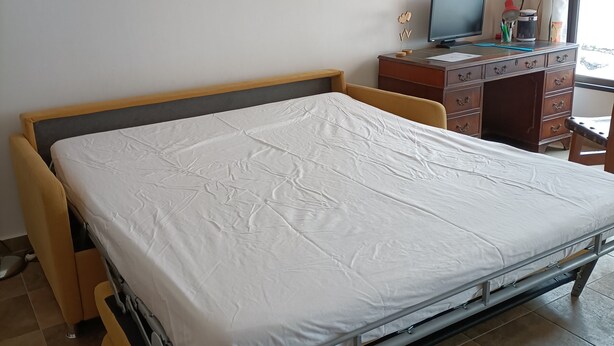 Ein Schlafzimmer mit einem Bett, einem Schreibtisch und zwei Bildern an der Wand.
