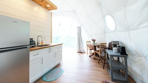 A compact kitchen with a refrigerator, sink, and wooden cabinets.