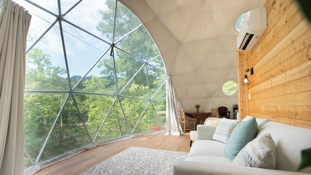 A cozy room with a large window, a sofa, and a wooden wall.