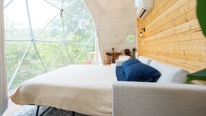 A cozy room with a large window, a bed, a table, and a chair.