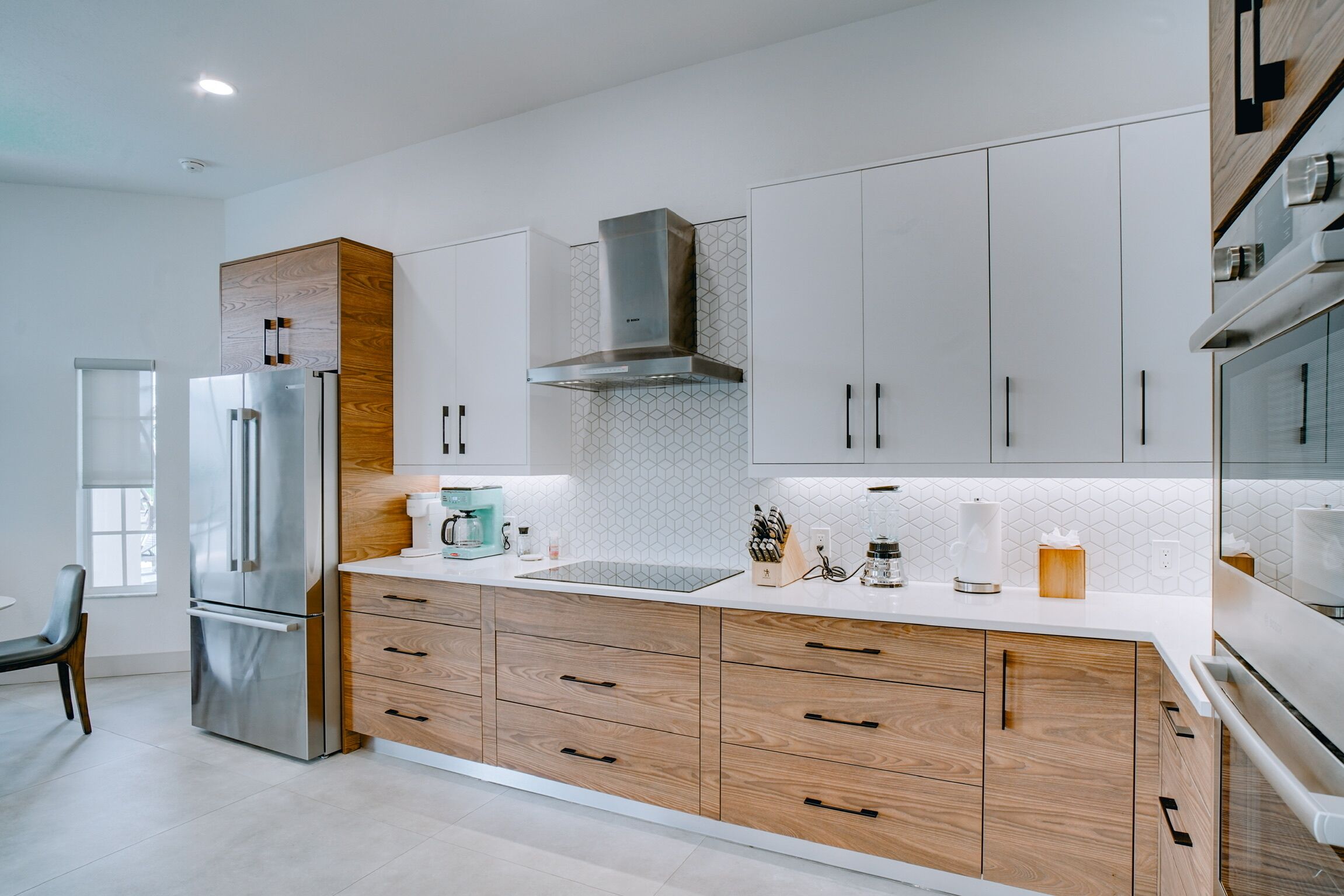 A modern kitchen with a stainless steel refrigerator, wooden cabinets, and a white countertop.