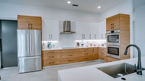 Una cocina moderna con electrodomésticos de acero inoxidable, armarios de madera y encimera blanca.