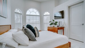 Un dormitorio con cama, televisión y escritorio con planta.