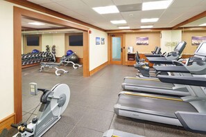 Une salle de sport équipée de tapis de course, de vélos elliptiques et de poids libres.