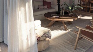 Un salon chaleureux avec un plafond en bois, une table basse ronde, un canapé et un coin repas avec des chaises.