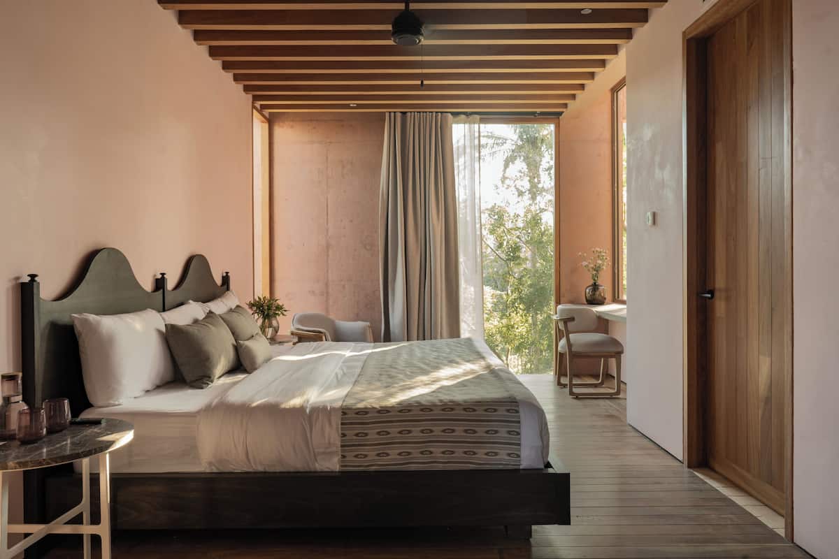 Un dormitorio moderno con una cama grande, techo de madera, una mesita pequeña y una silla.