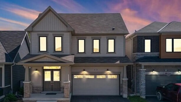 A two-story residential house with a garage, a driveway, and a well-maintained lawn. - Classy Home Near Beach & Airport

 (Hagersville)
