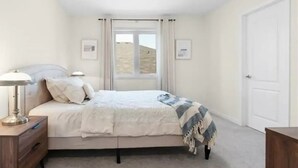 A bedroom with a bed, bedside table, lamp, and a window with curtains. - Classy Home Near Beach & Airport

 (Hagersville)