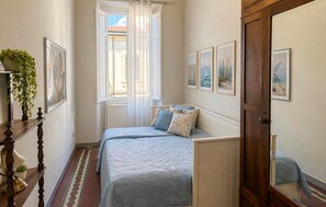 Une chambre à coucher avec un lit, une fenêtre, une porte et des tableaux accrochés au mur.