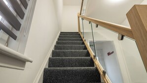 Un escalier avec une rampe en verre et des marches recouvertes de moquette.