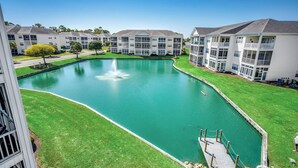 A residential building complex with a central pond, a fountain, and a dock. - Waterway views, beautiful sunsets, pools, hot tubs, balcony, grilling & beaches (North Myrtle Beach)