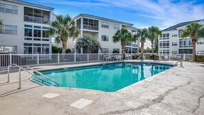 A swimming pool with a white fence, palm trees, and a multi-story building with balconies. - Waterway views, beautiful sunsets, pools, hot tubs, balcony, grilling & beaches (North Myrtle Beach)