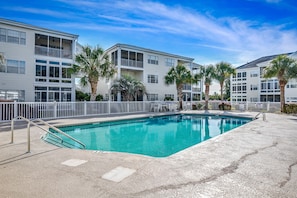 A swimming pool with a white fence, palm trees, and a multi-story building with balconies. - Waterway views, beautiful sunsets, pools, hot tubs, balcony, grilling & beaches (North Myrtle Beach)