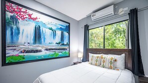 A hotel room with a large wall mural of a waterfall, a bed with white bedding, a nightstand, a lamp, and a window with curtains. - 18 Bedroom PRIVATE HOME Jaco Beach, 5-Year of Excellence, VIP Concierge Services (Puntarenas Province)