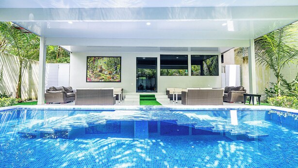 A modern outdoor pool area with a glass ceiling, two sofas, and a view of the surrounding greenery. - 18 Bedroom PRIVATE HOME Jaco Beach, 5-Year of Excellence, VIP Concierge Services (Puntarenas Province)