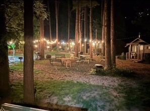 A row of cabins with string lights, surrounded by trees. - Cabin #1 - 1 Bedroom Modern With Fireplace (Gila County)