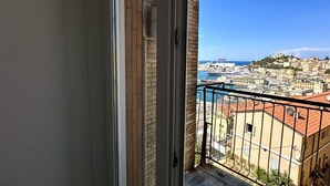 Un balcón con vista a una ciudad costera, incluyendo edificios y un puerto deportivo.