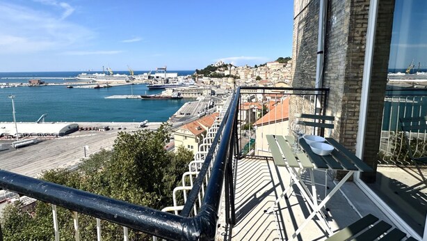 Un balcón con vistas a un puerto, que incluye barcos y edificios.