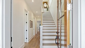 A modern interior with a wooden staircase, white walls, and a wooden floor. - Stunning Wild Dunes Home-- Fire Pit, Hot Tub, Golf Views, Walk to Marina!! (Isle Of Palms)