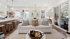 A modern kitchen with white cabinets, a central island, and bar stools. - Stunning Wild Dunes Home-- Fire Pit, Hot Tub, Golf Views, Walk to Marina!! (Isle Of Palms)