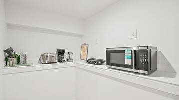 A kitchen with a microwave, toaster, coffee maker, and a small framed picture on the wall.