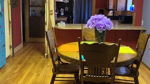 A dining area with a round table, four wooden chairs, and a vase with purple flowers. - Charming 2-bedroom house in Coleman with AC and WiFi.  Sleeps 6 & no pets. (Coleman)