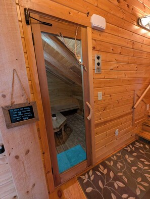 Een houten interieur met een deur naar een kamer, een thermostaat aan de muur en een bord met instructies.