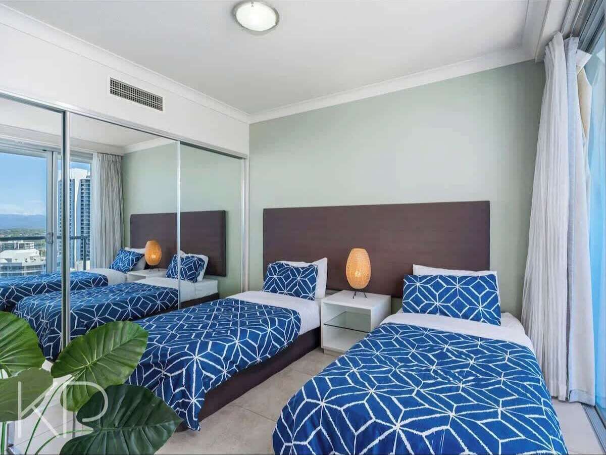 Ein Hotelzimmer mit zwei Betten, einem großen Fenster und Blick auf die Stadt.