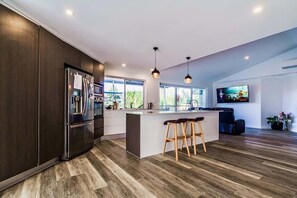 Una cocina moderna con una isla grande, armarios de madera oscura y una zona de asientos con taburetes de bar.