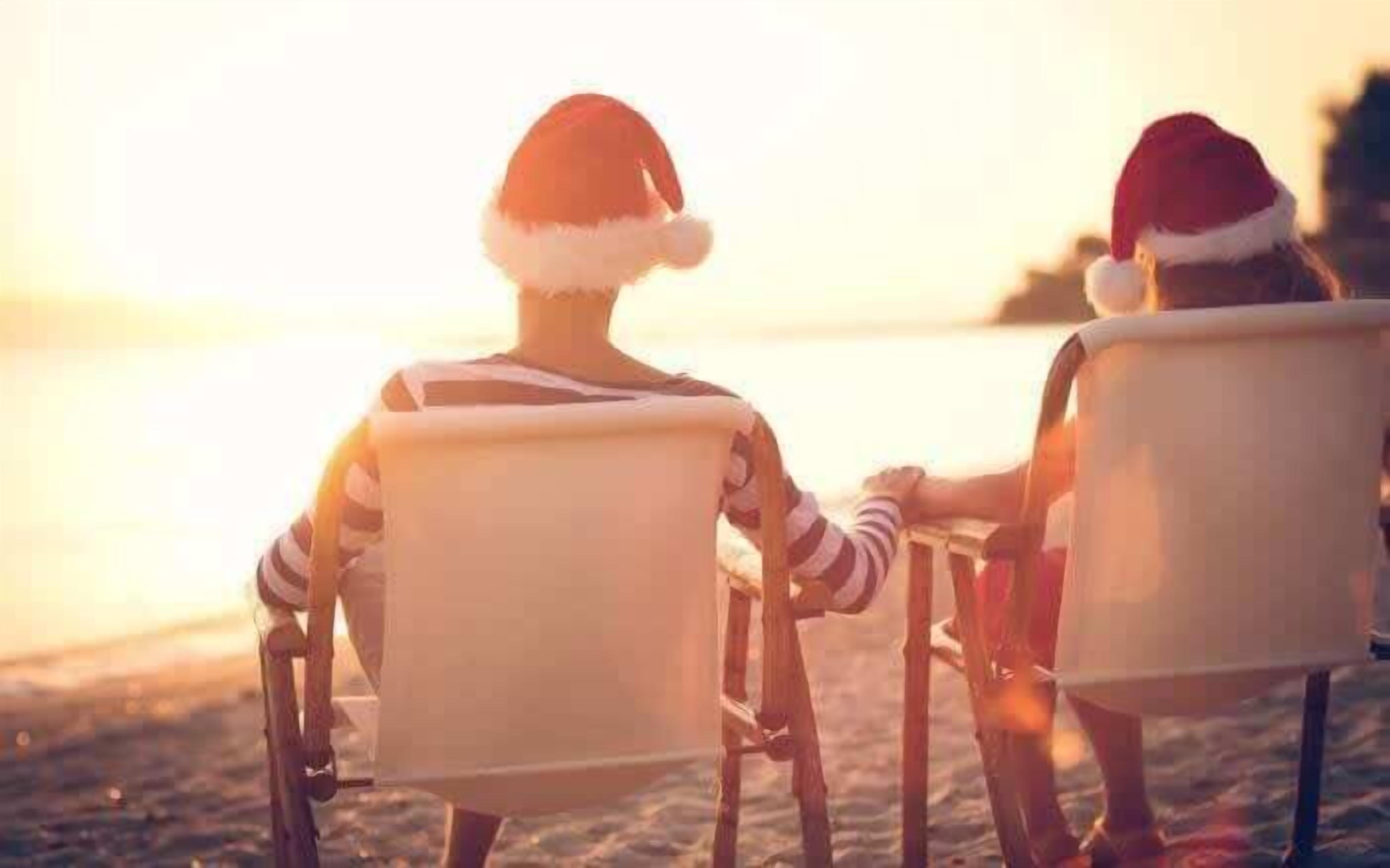 Deux personnes assises sur des chaises de plage, face à l’océan, au coucher du soleil.