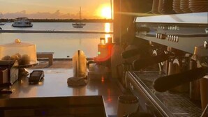 A kitchen with a view of boats on a body of water at sunset. - Vintage Coastal House | Fenced Pet-Friendly Yard (Labrador)