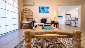 Une chambre avec un lit en bambou, une chaise en osier et une vue sur la cuisine.