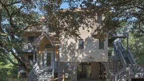 A two-story building with a wooden facade, a balcony, and a staircase leading to an upper level. - 4603-Yellow Brick Road - Southern Shores Escape w/ Pool & Hot Tub (Southern Shores)